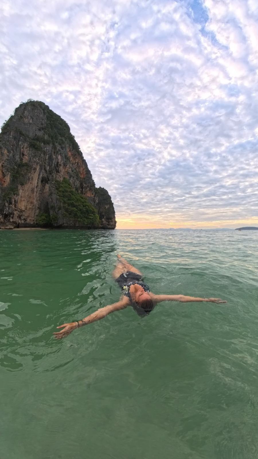 Laetitia qui flotte dans une eau calme au pied d'un rocher